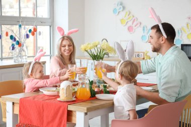 Meyveli tavşan kulaklı mutlu bir aile evde Paskalya yemeği yiyor.