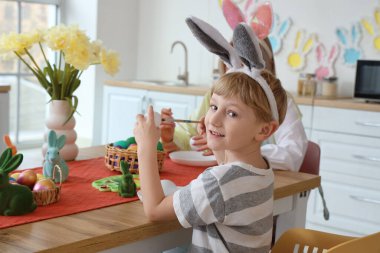 Annesiyle evde paskalya yumurtası boyayan tatlı bir çocuk.