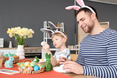 Babasıyla küçük şirin bir çocuk mutfakta paskalya yumurtası boyuyor.