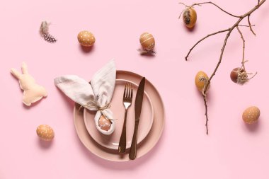 Paskalya yumurtaları, oyuncak tavşanlar ve pembe arka planda ağaç dalları olan güzel bir masa.
