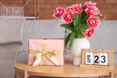 Çiçekli vazo, hediye kutusu ve takvim oturma odasındaki sehpanın üzerinde.