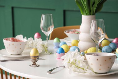 Bayramlık Paskalya sofrası, boyanmış yumurtalar, bardaklar ve çiçekler