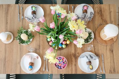 Güzel masa dekorları, boyanmış yumurtalar, Paskalya pastası, çatal bıçak takımı ve çiçek vazosu.