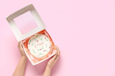 Pembe arka planda tatlı bento keki olan kadın elleri. Uluslararası Kadınlar Günü