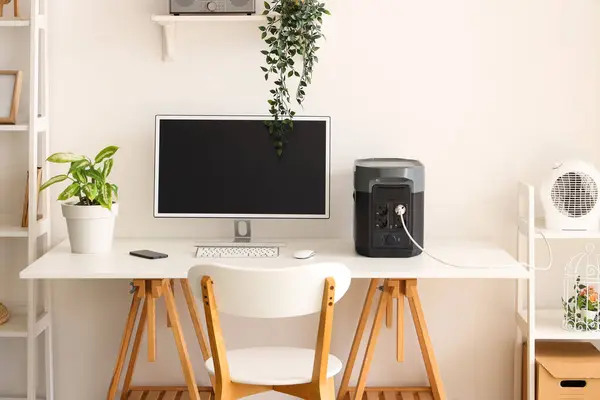 Comfortable workspace with modern computer and portable power station