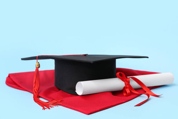 Mortar board and diploma on blue background