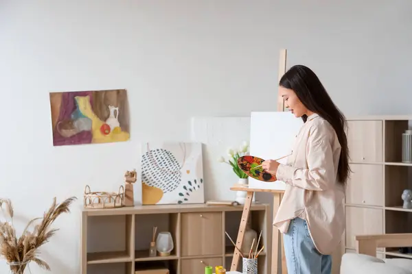 Stock image Female Asian artist drawing on easel at home