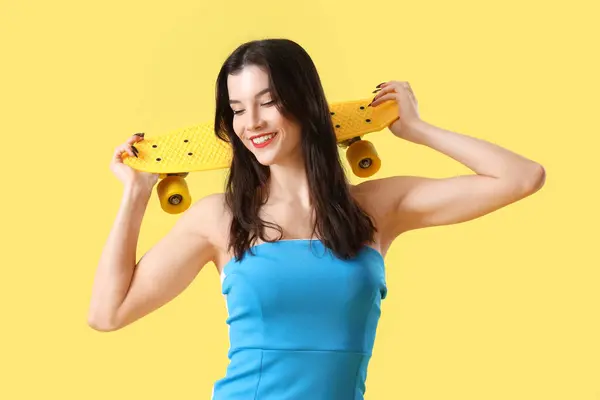 Piękna Młoda Kobieta Stroju Plażowym Deskorolką Żółtym Tle — Zdjęcie stockowe