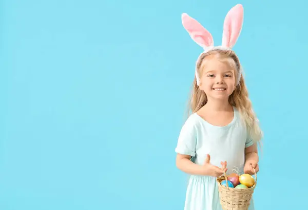 可爱的小女孩 戴着蓝色背景的复活节彩蛋 长着小兔子耳朵 — 图库照片