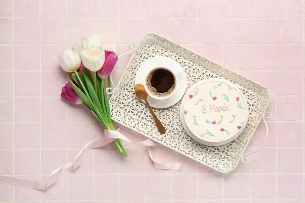 Sweet bento cake with cup of coffee and beautiful tulips on pink tile background. International Women\'s Day