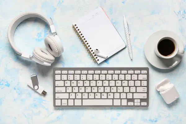 Notebook, computer keyboard and headphones on blue grunge background
