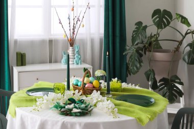 Paskalya kutlaması için boyanmış yumurta, çelenk ve yanan mumlarla servis edilen şenlik masası oturma odasında.