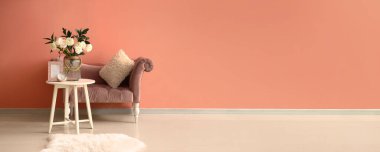 Ranunculus çiçekli bir masa ve pembe duvarın yanında yumuşak bir koltuk. Tasarım için pankart