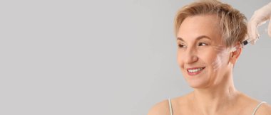 Gri arkaplanda metin için boşluk olan doldurucu enjeksiyon alan olgun kadın