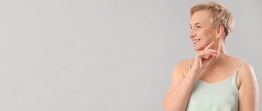 Işık arkaplanına karşı doldurma işlemi için yüzünde işaretler olan olgun bir kadın.