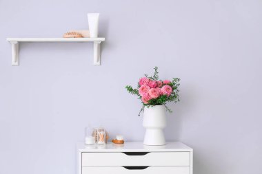 Güzel pembe yıldız çiçekleri ve banyo malzemeleriyle dolu bir vazo tuvalette.