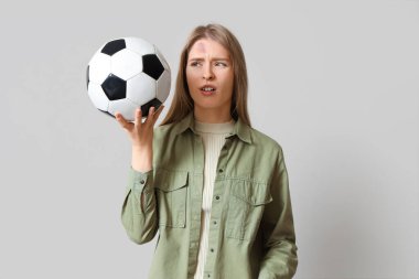 Beyin sarsıntısı geçiren ve arka planda futbol topu olan genç bir kadın.