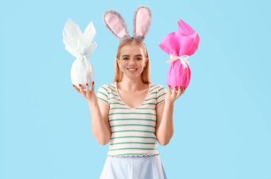 Paskalya hediyeleri ve mavi arka planda tavşan kulaklı genç kız.