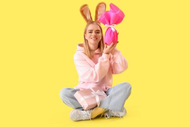 Paskalya tavşanı kulaklı genç kız ve sarı arka planda hediyeler