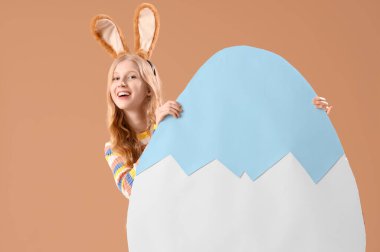 Paskalya tavşanı kulaklı genç bir kız ve bej arka planda büyük bir kağıt yumurta.
