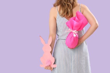 Kağıttan tavşanı olan genç bir kız ve leylak arka planda Paskalya hediyesi.