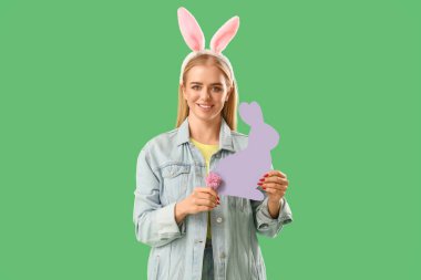 Paskalya tavşanı kulakları ve yeşil arka planda kağıt tavşanı olan genç bir kız.
