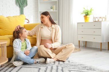 Hamile annesi evde oturan tatlı küçük bir kız.