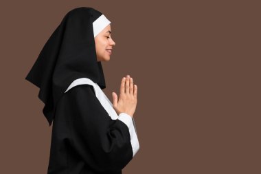 Kahverengi arka planda dua eden genç bir rahibe