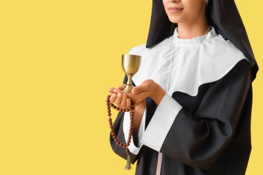 Sarı arka planda boncuklu ve kadehli genç rahibe.