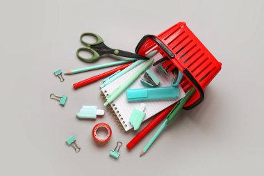 Gri arka planda farklı okul kırtasiyesi olan alışveriş sepeti.