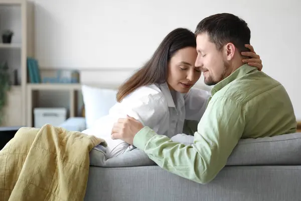 stock image Happy young couple sitting on sofa at home