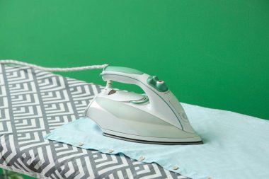 Yeşil arka planda elektrikli ütü, yakın planda.