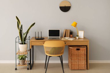 Ofisteki ışık duvarının yanında kablosuz ağ yönlendiricisi ve dizüstü bilgisayarı olan modern işyeri