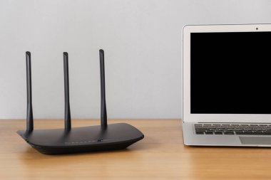 Modern Wi-Fi yönlendirici. Bilgisayarı ışık duvarının yanındaki masada. Yakın plan.