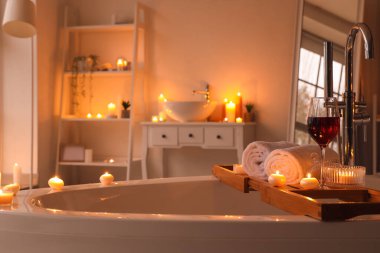 Banyoda şarap, havlu ve yanan mumlarla dikil.