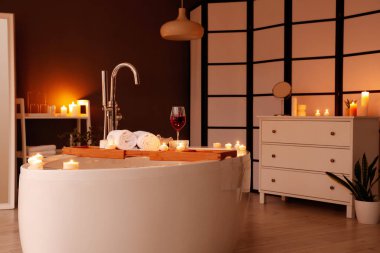 Şarap, havlu ve yanan mumlarla dolu küvet.