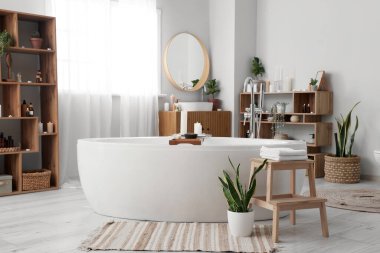 İçinde yanan mumlar, küvet ve raf üniteleri olan şık bir banyo.