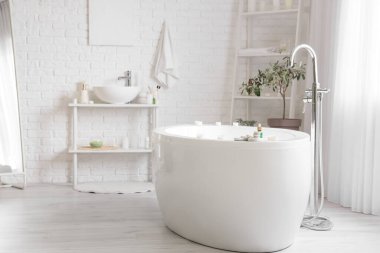 Küvette yanan mumlar ve spa taşlarıyla aydınlık odada