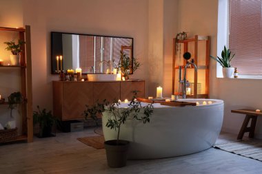 Geceleri yanan mumlar, lavabo ve küvetin olduğu banyonun içi.