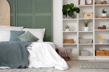 Raflar ve bitkilerle aydınlık yatak odasının içinde.