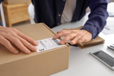 Depodaki müşteriler için paketleme paketi hazırlayan bir erkek çevrimiçi mağaza satıcısı.