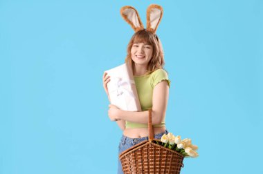 Paskalya tavşanı kulaklı genç kız, mavi arka planda sepet ve hediye.