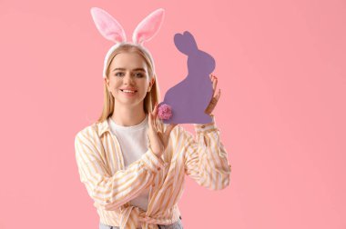 Paskalya tavşanı kulakları ve pembe arka planda kağıt tavşanı olan genç bir kız.