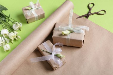 Yeşil arkaplanlı hediye kutuları, makas ve güller. Kadınlar Günü kutlaması