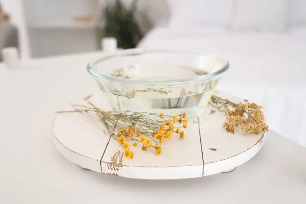 Bowl of water with herbs for steam inhalation on table in bedroom, closeup