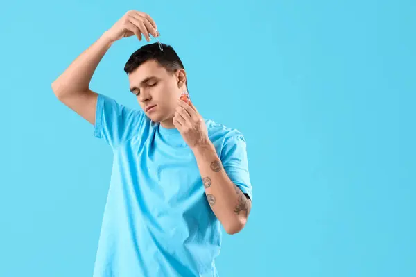 Genç Adam Mavi Arka Planda Saç Büyütmek Için Serum Kullanıyor — Stok fotoğraf