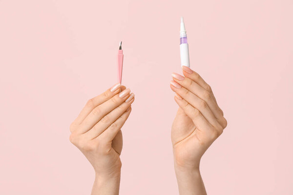 Руки женщины с ручкой из кутикулы и резаком на розовом фоне