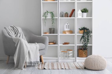 Oturma odasının içinde koltuk, raf ünitesi ve yapay bitkiler var.