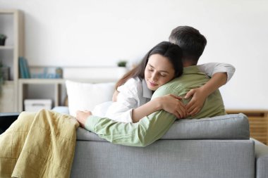 Evdeki kanepede sarılan mutlu genç çift.