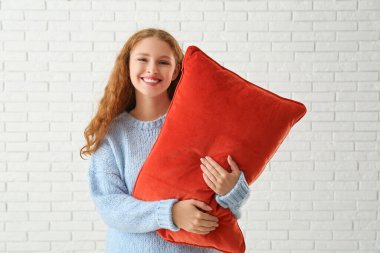 Beyaz tuğlalı kırmızı yumuşak yastıklı mutlu genç kadın.